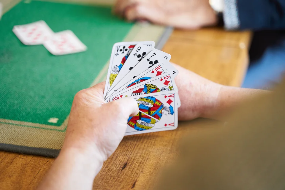 A person holding real playing cards during a casual indoor card game.